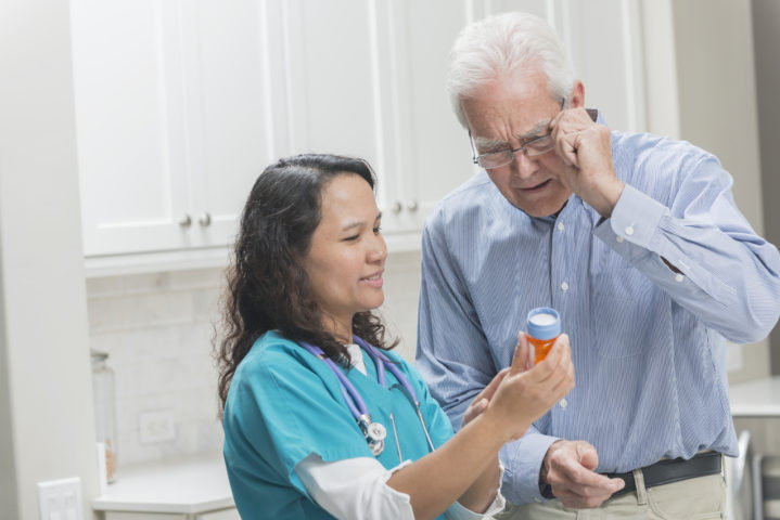 caregiver and senior man looking over medication for chronic illness